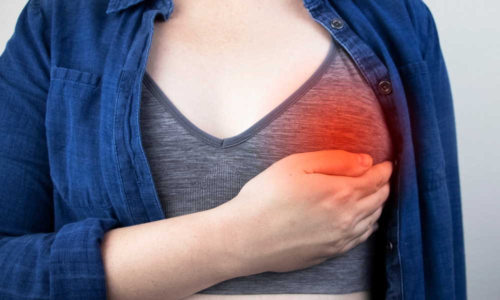 Person experiencing sharp pain under the left breast indicating possible chest wall or rib-related pain